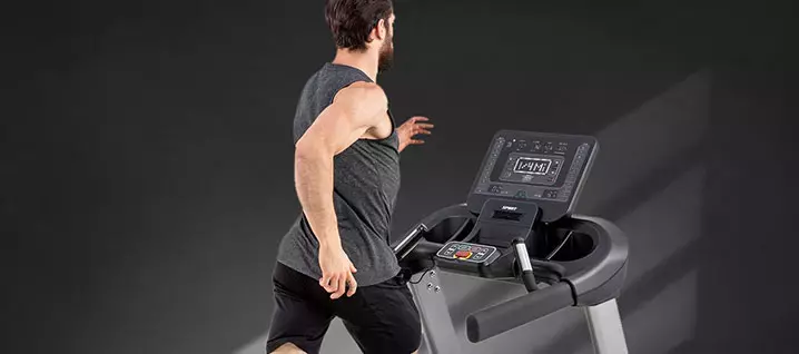A man is running on a treadmill in a gym .